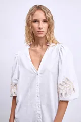 Vestido blanco de lino con escote en V, mangas cortas abullonadas y bordados florales en beige en mangas y ruedo.