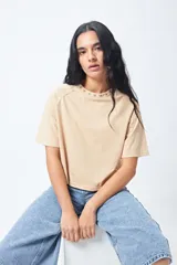 Remera blanca de manga corta con mangas ranglan y cuello redondo. El cuello tiene un bordado de estrellas negras alrededor.