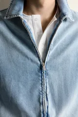 Cazadora de denim de algodón con efecto lavado, corte cropped, cuello solapa, cierre frontal con cremallera de doble dirección, manga larga con puños abotonados y bolsillos laterales.