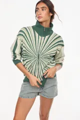 Campera de punto de algodón y acrílico, con diseño geométrico radial en tonos verdes y blanco, cuello alto y cierre frontal completo.
