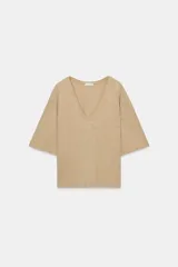 Remera de corte regular fit y diseño holgado, color beige, con profundo escote en V y mangas cortas amplias.