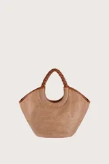 Bolso tipo shopper de textura tejida en color natural, con asas superiores trenzadas en tono marrón y detalles de ribetes en cuero sintético. Incluye un colgante decorativo de cuero con logo grabado.
