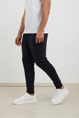 Pantalón jogging de corte slim, con puños elastizados, cintura con cordón ajustable, cierres laterales engomados y bolsillo tipo parche lateral.