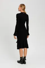 Falda midi negra de tejido de punto acanalado, con silueta ajustada, bajo acampanado y detalle de lazos entrecruzados en el lateral.