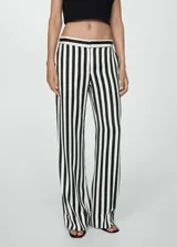 Pantalón largo de tela fluida con estampado de rayas verticales en blanco y negro. Diseño recto con bajo con vuelta, cierre oculto de botón, gancho y cremallera, y dos bolsillos laterales.