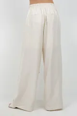 Pantalón beige de pierna ancha, confeccionado en tela suave con finos destellos dorados, diseño forrado y sobre tela drapeada a modo de cinturón.