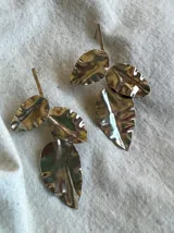 Aros colgantes plateados con forma de hojas con nervaduras.