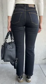 Pantalón de jean negro con costuras a la vista color ocre.