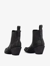 Bota corta estilo cowboy negra, de cuero, con punta afilada y taco ancho y bajo. Presenta bordados tonales en la caña y en la puntera.