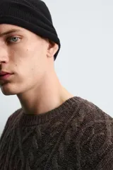 Jersey de punto con diseño de trenzas, cuello redondo y manga larga. Presenta un acabado en rib en puños y ruedo, con un efecto de lavado que le otorga una apariencia única.