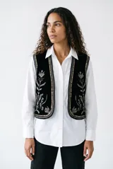 Chaleco de terciopelo negro con bordados florales y detalles de lentejuelas en los bordes.