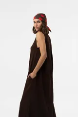 Vestido midi sin mangas de color marrón, confeccionado con textura arrugada, escote redondo, silueta relajada y caída liviana, con un lazo fino ajustable en la cintura.