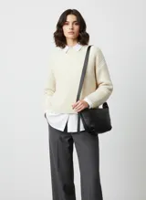 Bolso de hombro negro de efecto cuero, con correa ancha y ajustable. Diseño de media luna o 'hobo' con cierre superior.