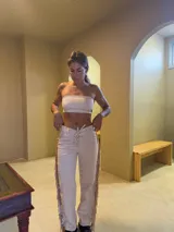 Pantalón de gamuza color beige con flecos en los laterales, tiro alto y corte recto.