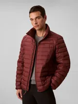 Campera puffer ligera de Calvin Klein, color bordó, con acolchado de canales horizontales, cuello alto y cierre frontal de cremallera. Presenta un diseño minimalista con logo de la marca en el pecho.