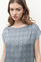 Blusa beige con estampado geométrico, cuello redondo y mangas cortas.