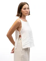Musculosa de lino color blanco, con cuello redondo y diseño de laterales abiertos unidos por tres tiras horizontales.
