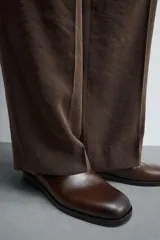 Zueco de cuero color marrón con forro y plantilla de cuero, horma cuadrada y suela con ligero tacón.