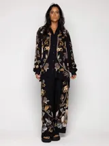 Pantalón de viscosa negro con estampado floral en tonos dorados, marrones y grises.