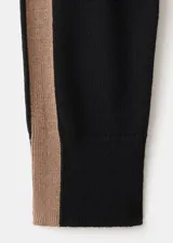 Chaleco de punto negro con diseño de cuello redondo y franjas laterales en color tostado. Presenta un corte holgado y estilo minimalista.