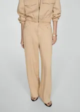 Pantalon de corte recto y tejido fluido, color beige, con cierre frontal de cremallera y botón, trabillas para cinturón y bolsillos laterales.