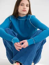 Polera básica de algodón en tejido rib, color turquesa, de manga larga, con hombreras y detalles de pespuntes en color contrastante en las terminaciones y el cuello.