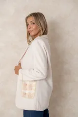 Blazer de lana soft color camel, con corte recto y solapas clásicas. Presenta detalles de encaje blanco en los puños y apliques de perlas en los bolsillos frontales.