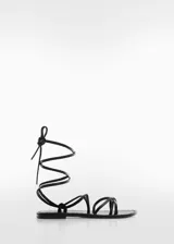 Sandalia plana negra de cuero con tiras finas que se atan al tobillo.