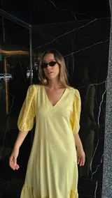 Vestido largo color amarillo pálido, con escote en V, mangas cortas abullonadas con detalle de calado y ruedo con volantes y calado.