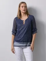 Blusa Harper de microtul estampado azul con lunares blancos, cuello redondo, escote en U con aplique de aros y mangas cortas amplias.