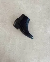 Botín Chelsea de cuero vacuno negro con detalle de metal plateado en la puntera y elástico lateral.