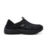 Zapato tipo slip-on negro, diseñado para enfermeras y profesionales de la salud, con capellada de material sintético y paneles de malla transpirable. Presenta un diseño sin cordones con un tirador trasero para facilitar el calce y una suela gruesa y deportiva.