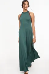 Vestido largo azul marino, de corte fluido, con escote halter, detalles trenzados en los hombros, bolsillos laterales y tajo profundo en la pierna.