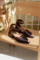 Zapatos de cuero color chocolate con diseño de punta cuadrada, taco bloque bajo y tira ajustable al tobillo con hebilla metálica.