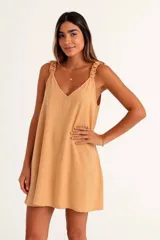 Vestido corto color amarillo mostaza, con escote en V y tirantes finos con detalle de volado o fruncido. El ruedo es asimétrico.