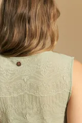 Top sin mangas de jacquard color negro, con cuello cerrado y silueta recta. Presenta una textura trabajada con relieve y una terminación suavemente ondulada en el ruedo.