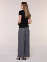 Remera básica de corte al cuerpo con textura acanalada, cuello redondo y mangas cortas. Presenta una pequeña placa metálica decorativa en el borde inferior.