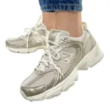 Championes New Balance modelo 530, con diseño retro inspirado en el running. Presenta una estructura de malla transpirable con revestimientos sintéticos en tono dorado metálico. Cuenta con entresuela con tecnología ABZORB para una amortiguación superior y suela de goma resistente.