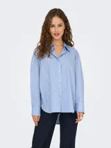 Camisa de manga larga con cuello clásico y cierre frontal de botones. Presenta un diseño de rayas verticales blancas sobre fondo azul claro, con corte holgado y puños anchos.
