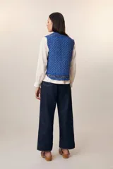 Chaleco acolchado azul con estampado floral, cuello redondo y cierre frontal con botones de madera.