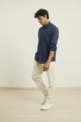 Camisa de manga larga confeccionada en una mezcla de algodón y lino, con cuello abotonado, cierre frontal de botones y un bolsillo en el pecho.