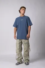 Remera oversize de algodón pesado color azul, con bordado "HUMAN" centrado en el pecho y hombros ligeramente caídos.