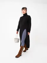 Buzo largo de tejido de punto grueso color negro, con cuello alto y tajo lateral.