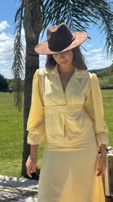 Camisa blanca con lunares celestes, de corte clásico, con cuello camisero y mangas largas abullonadas.