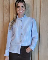 Camisa de manga larga con estampado de rayas verticales en tonos crudo y beige. Presenta cuello alto con volados, cierre frontal con botones dobles y puños con volados.