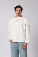 Buzo de tejido waffle color blanco, con cuello redondo, mangas largas y corte relajado. Presenta un pequeño estampado minimalista en el pecho con el texto VCP CNPT.
