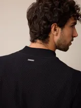 Sweater de punto color negro, con cuello alto y cierre frontal parcial tipo medio cierre. Presenta textura en el tejido y logo bordado en el pecho.