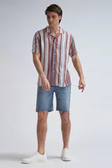 Camisa de manga corta con cuello solapa y cierre frontal con botones. Presenta un estampado de rayas verticales en tonos marrón, azul y blanco.