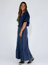 Pollera larga de jean azul con corte acampanado y costuras verticales en color ladrillo.