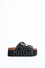 Sandalia plataforma de diseño estilo Birkenstock en color negro, con dos tiras ajustables con hebillas metálicas, decoradas con múltiples tachas y ojales plateados.